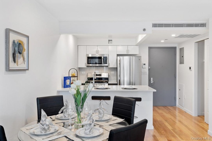Dining room with light wood-type flooring, recessed lighting, and electric panel