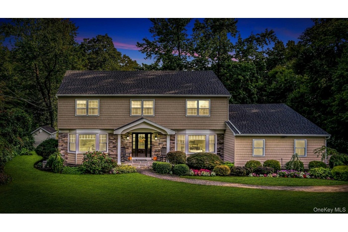 Colonial home featuring a shingled roof and a front yard