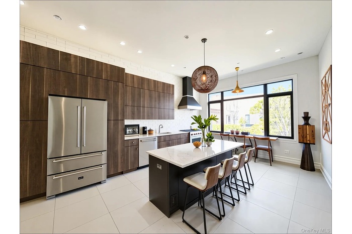Kitchen featuring high end appliances, modern cabinets, dark brown cabinetry, light tile patterned flooring, and a kitchen island