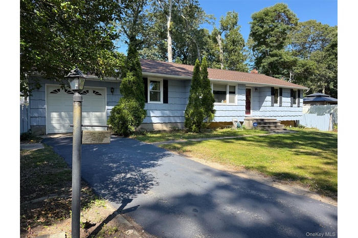 Ranch-style house featuring a chimney, driveway, and an attached garage