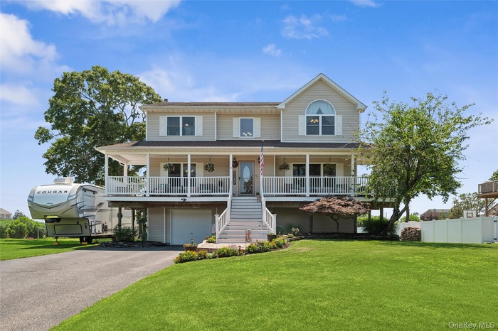 View of front of property with covered porch, stairs, an attached garage, and asphalt driveway