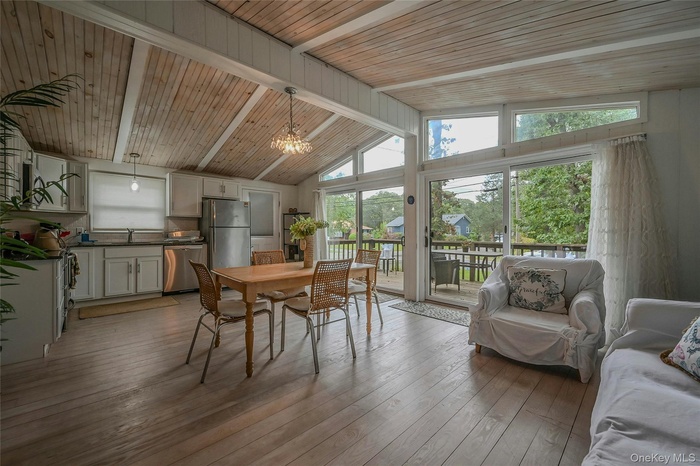 Dining space with healthy amount of natural light, light wood-style floors, a chandelier, and wooden ceiling
