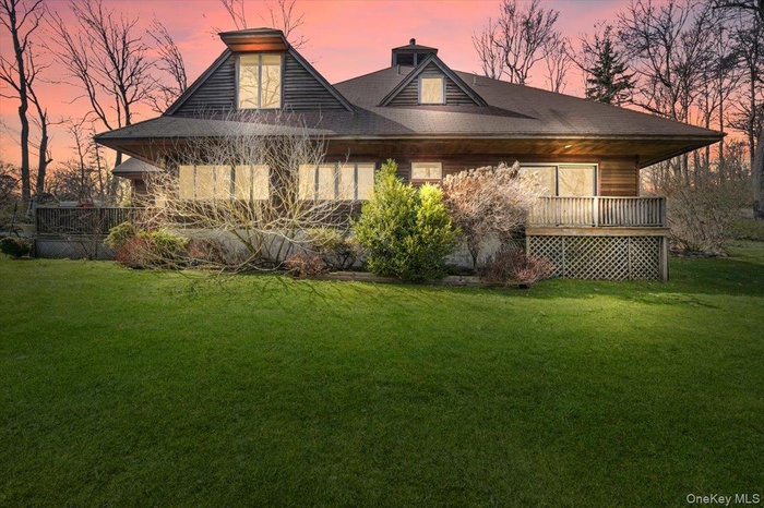 Back of house at dusk featuring a yard and a chimney