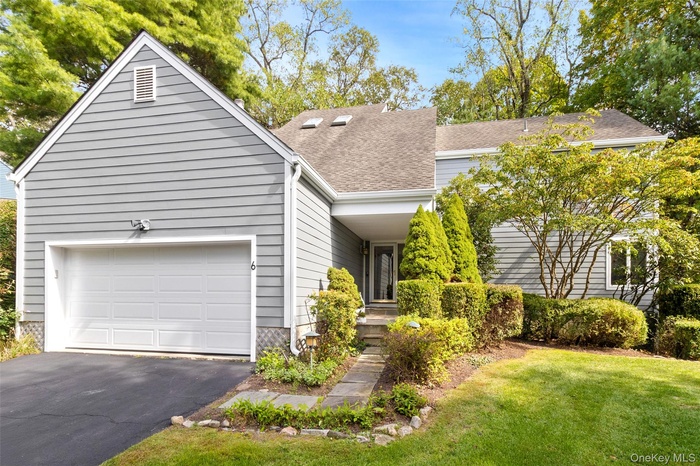 View of front facade with driveway, roof with shingles, a garage, and a front lawn