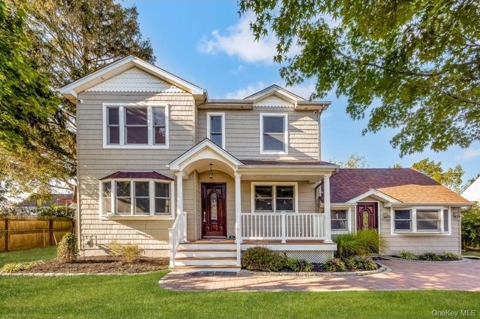 View of front of property with covered porch and a front lawn