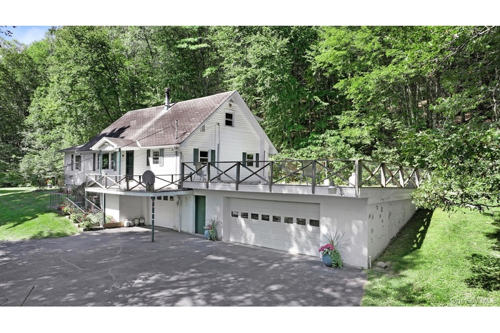 View of front of home with asphalt driveway, a front lawn, stairs, stucco siding, and an attached garage