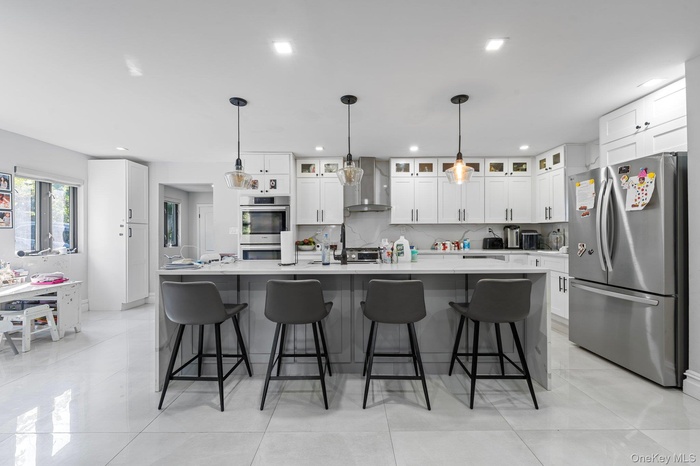 Kitchen with stainless steel appliances, an island with sink, a breakfast bar area, backsplash, and recessed lighting