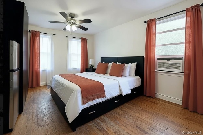 Bedroom with light wood-style floors, a ceiling fan, and cooling unit