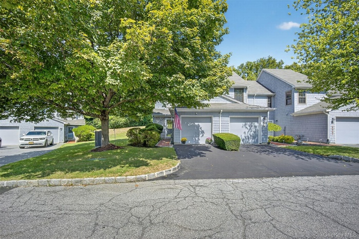 View of front of home featuring asphalt driveway, a front yard, and a garage