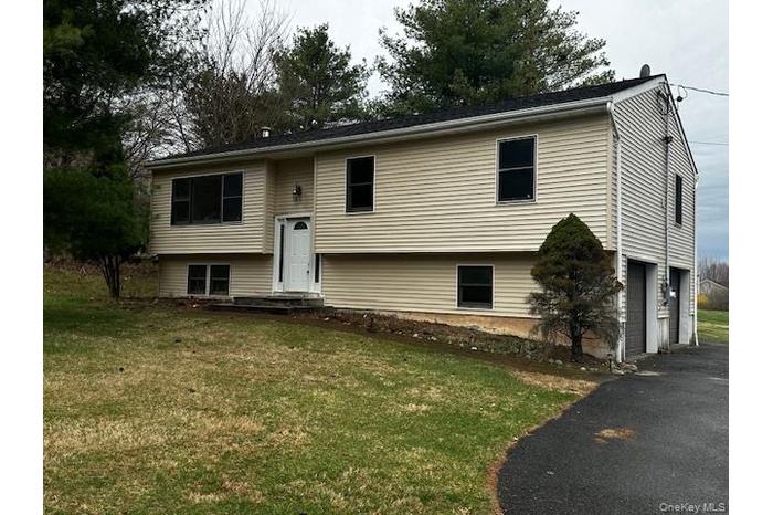 Bi-level home featuring a front yard, an attached garage, and aphalt driveway