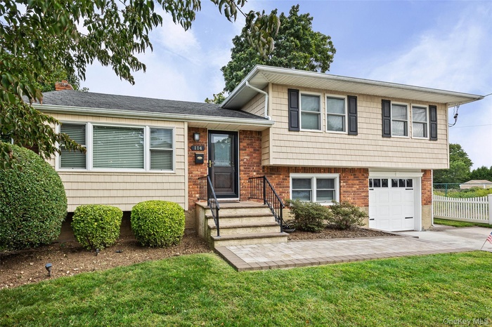 Tri-level home featuring a garage, brick siding, concrete driveway, and roof with shingles