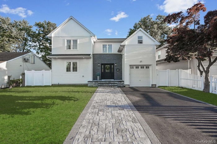 View of front of property featuring driveway, board and batten siding, a gate, and a garage