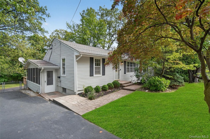 View of front of home with a shingled roof and a front lawn