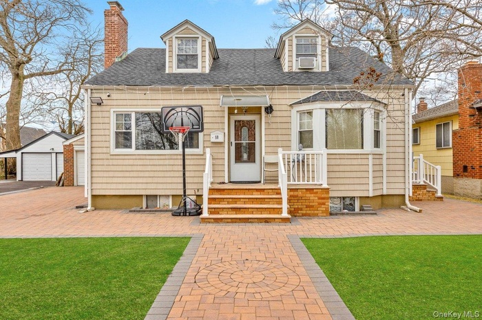 New england style home with a chimney, a front yard, an outdoor structure, and roof with shingles
