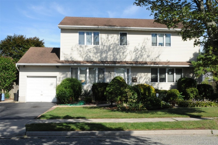 Traditional home featuring a garage, driveway, and a front lawn
