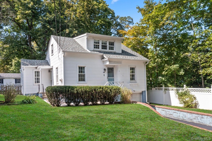 Bungalow-style home with roof with shingles, a garage, a porch, and view of scattered trees