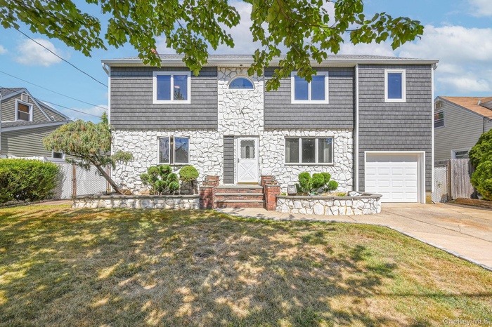 View of front of property with stone siding, driveway, and an attached garage