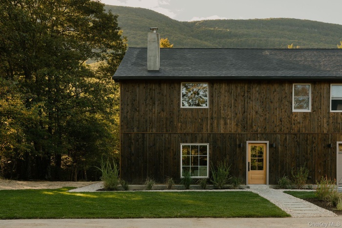View of front of house featuring a front yard, a chimney, and a mountain view