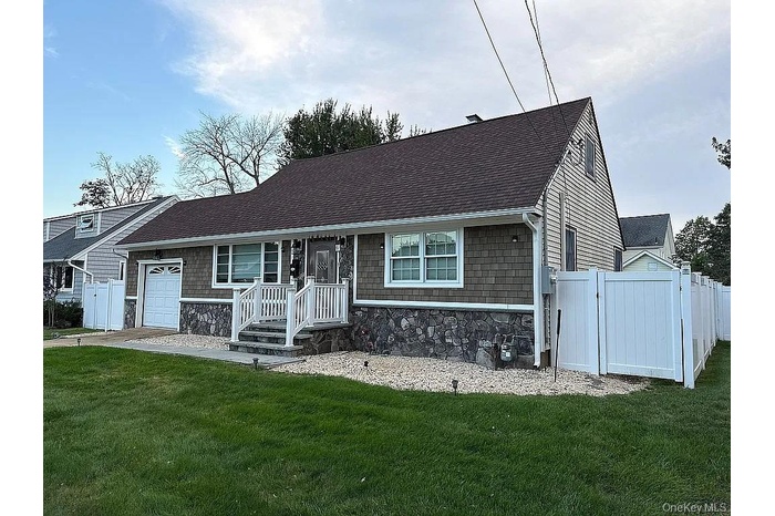 View of front of house featuring stone siding, a shingled roof, a gate, and a garage