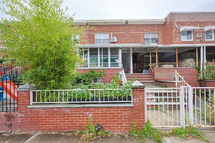 Traditional-style home featuring a gate, a fenced front yard, and brick siding
