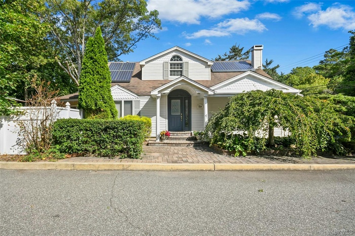 View of front of property with roof mounted solar panels, a chimney, and roof with shingles