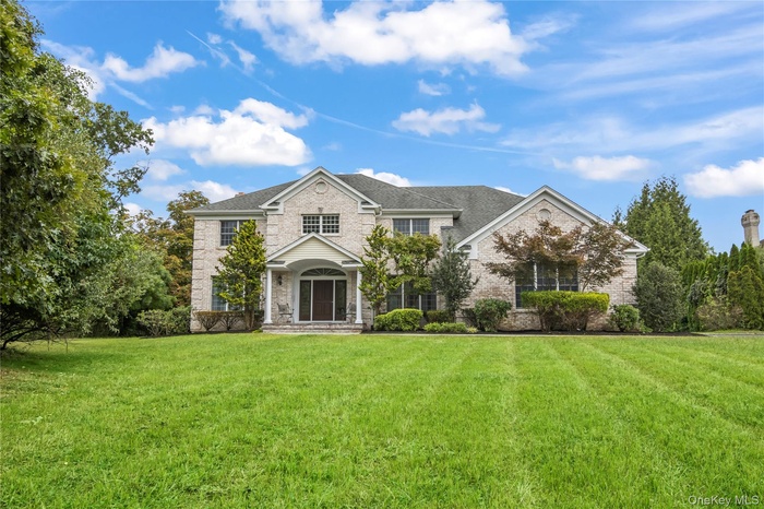 Traditional-style home with a front lawn, brick siding, a porch, and stone siding