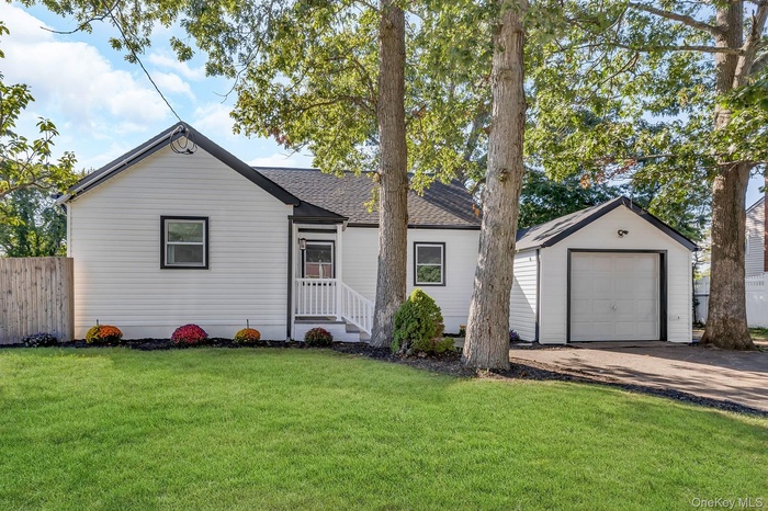 Ranch-style house featuring a shingled roof, an outdoor structure, driveway, and a detached garage
