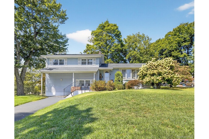 Split level home with a chimney, a front lawn, and a porch