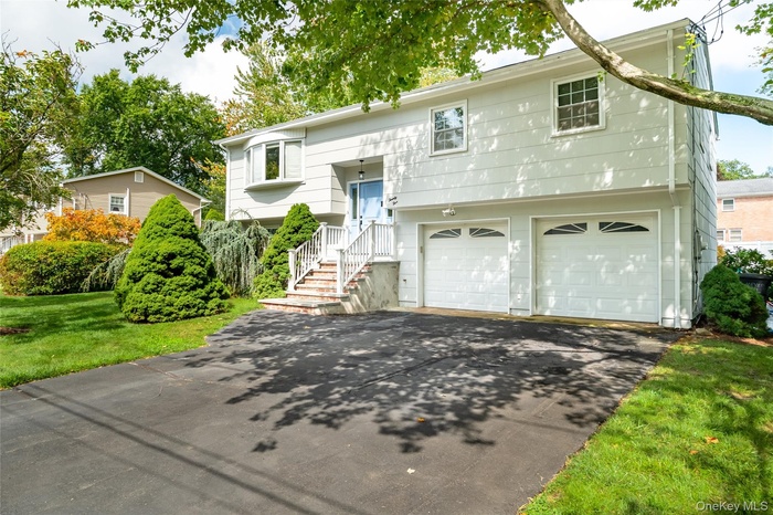 Split foyer home featuring an attached garage, driveway, and a front lawn