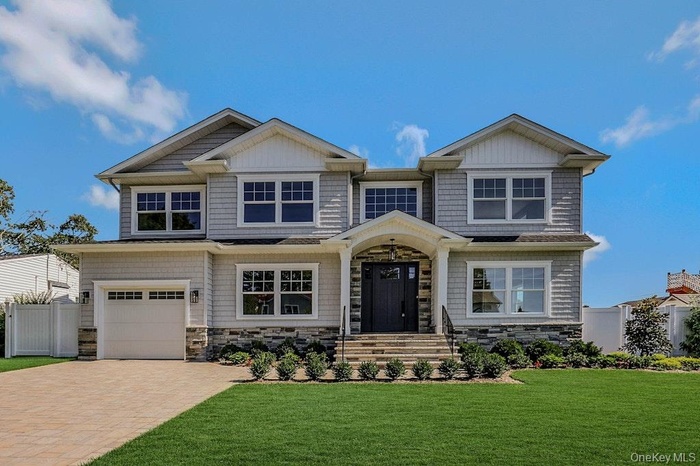 View of front of property featuring stone siding, an attached garage, and decorative driveway