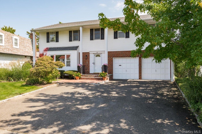 View of front of house with driveway, brick siding, and an attached garage
