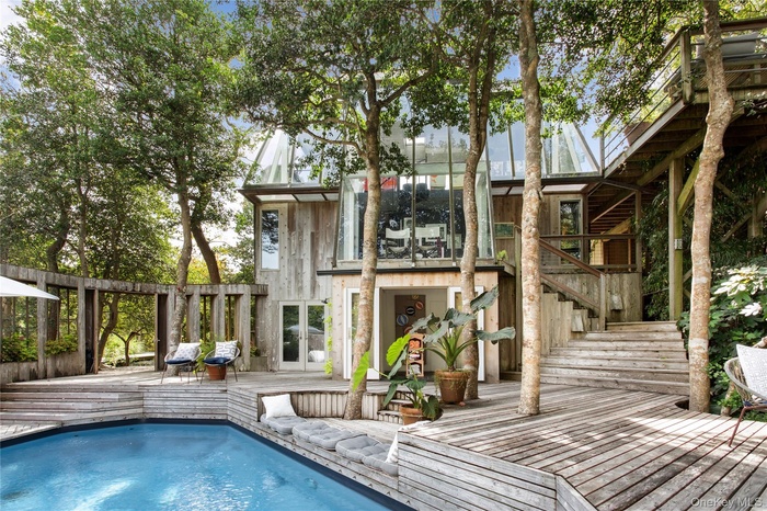 Rear view of property with a wooden deck, stairway, an outdoor pool, and french doors