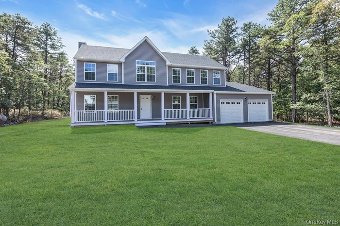 Colonial inspired home with covered porch, asphalt driveway, a front lawn, a shingled roof, and an attached garage