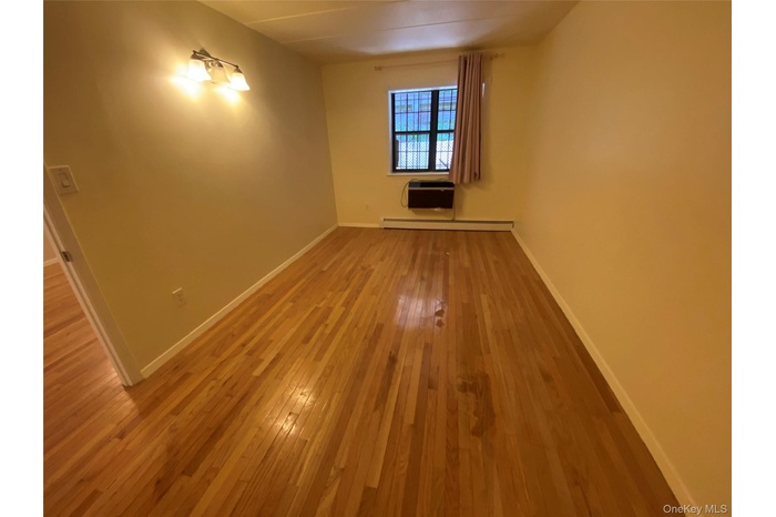 Spare room with baseboard heating, light wood-type flooring, and a wall mounted AC