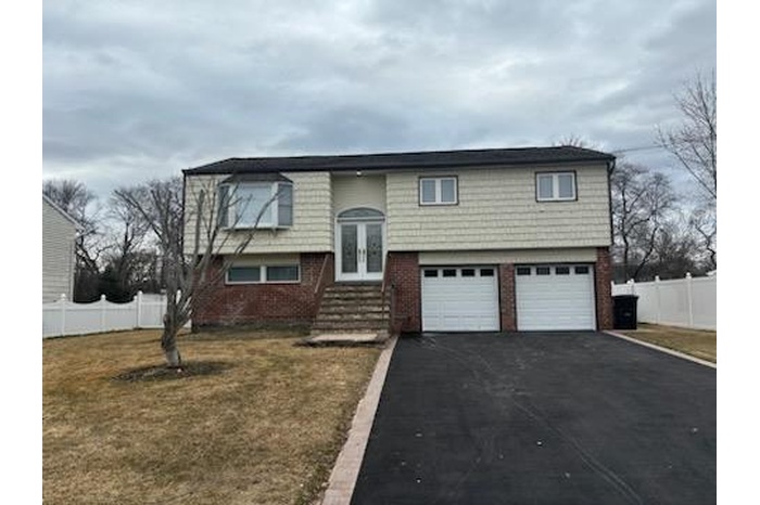 Bi-level home featuring driveway, fence, french doors, a front lawn, and brick siding