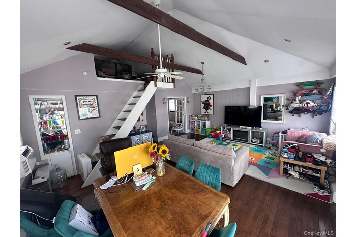 Living area with beam ceiling, wood finished floors, ceiling fan, stairs, and a chandelier
