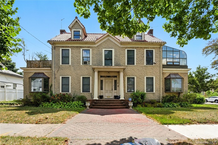View of front of home featuring a chimney, a front lawn, and stucco siding