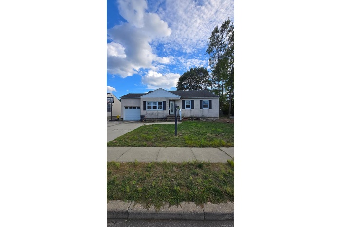 Ranch-style house with a front lawn, concrete driveway, and a garage