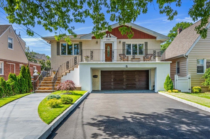 View of front of home featuring asphalt driveway, an attached garage, brick siding, stairway, and stucco siding
