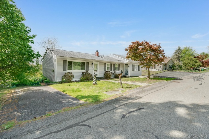 Single story home with a chimney and a front lawn