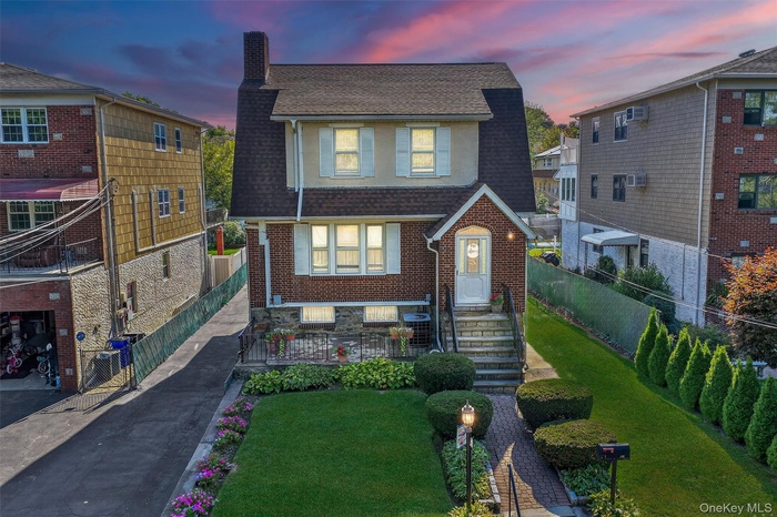 View of front of home featuring a chimney, a shingled roof, asphalt driveway, and brick siding