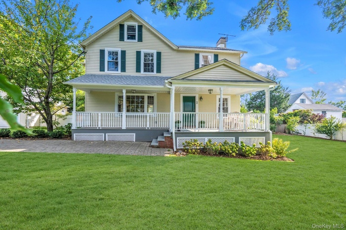 View of front of house with covered porch, a chimney, a front yard, and a shingled roof