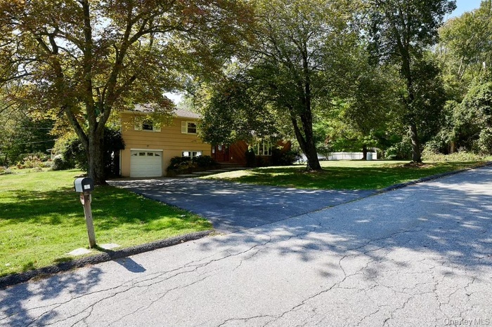 View of front of house with driveway, a front lawn, and an attached garage