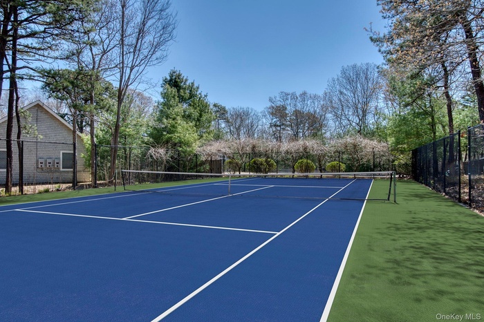 View of tennis court with community basketball court and view of wooded area