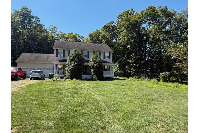 Colonial house featuring a front yard, a porch, driveway, and view of scattered trees