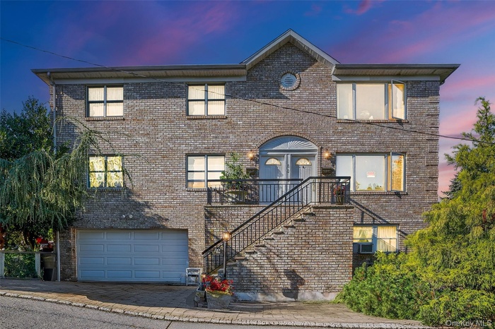 Traditional-style home with stairway, brick siding, driveway, and a garage