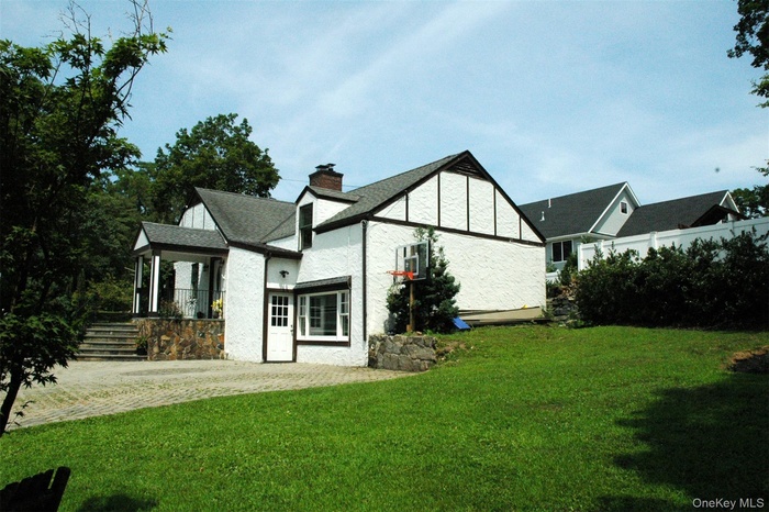 Rear view of property featuring a yard, a chimney, and stucco siding