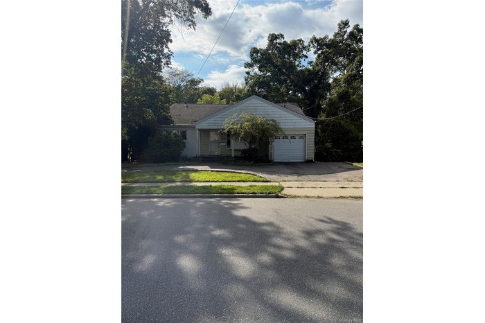 View of front of home with driveway, covered porch, a garage, and a front lawn