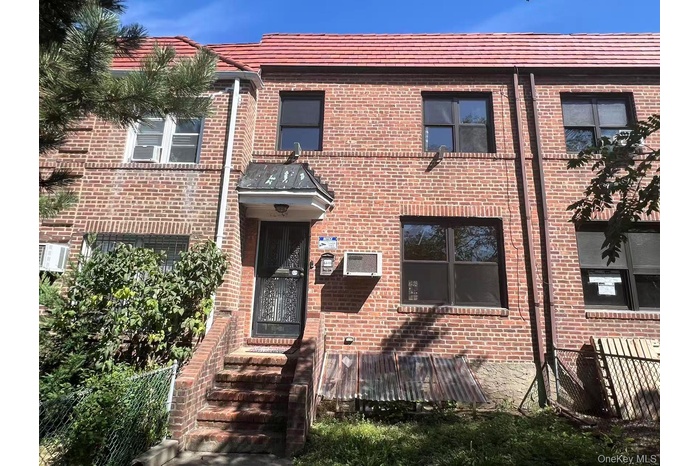 View of front facade featuring brick siding and an AC wall unit