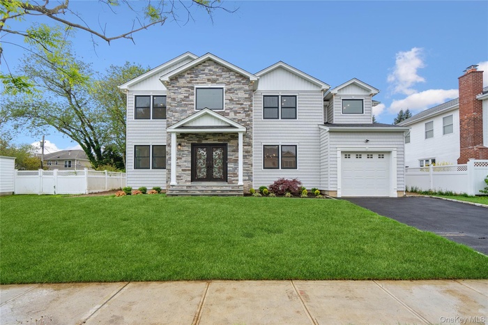 View of front of house featuring board and batten siding, asphalt driveway, and stone siding